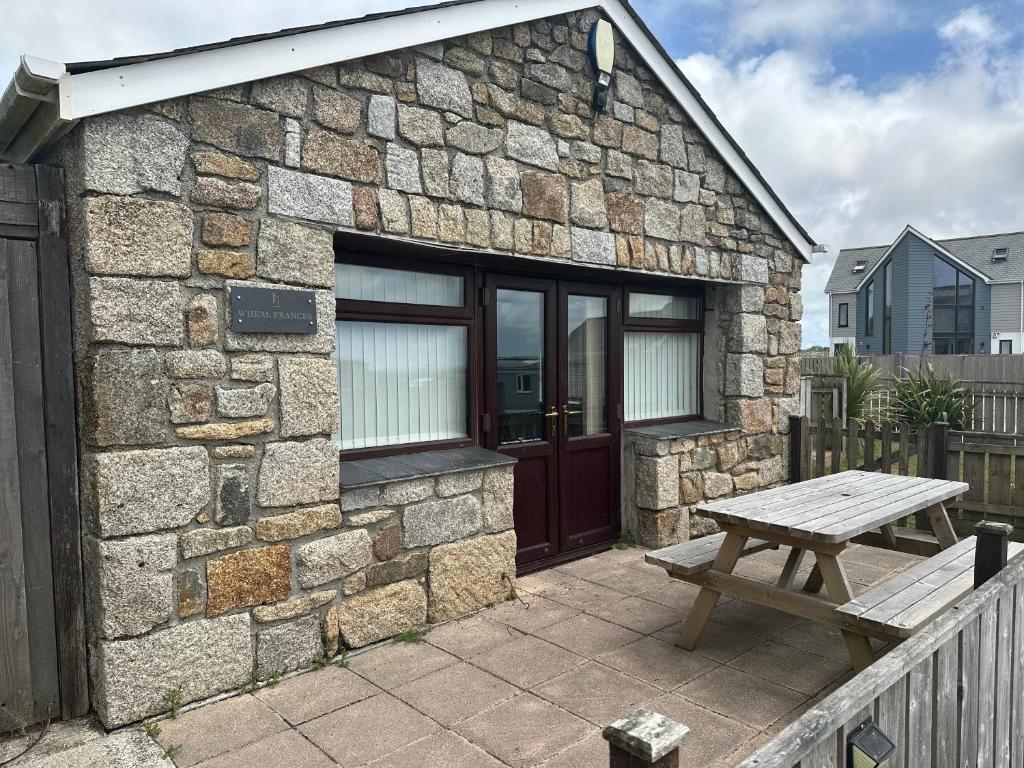 a stone building with a picnic table in front of it at Wheal Frances-Beautifully Fitted Bungalow Helston Cornwall in Helston