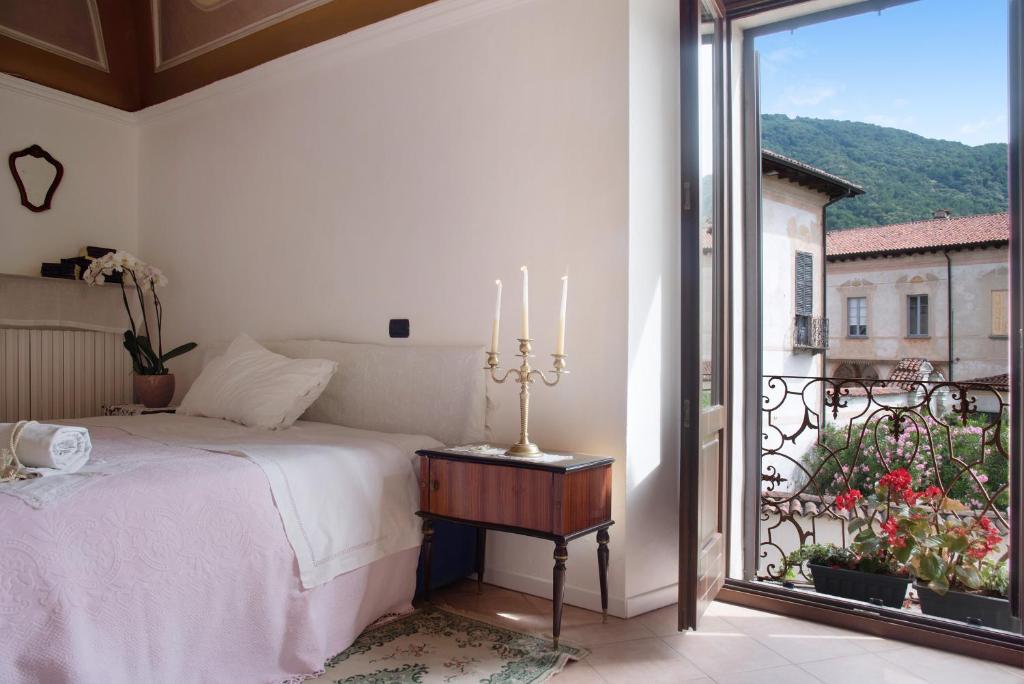 a bedroom with a bed and a balcony with a view at Dimora Ettore - Lago Maggiore in Casalzuigno