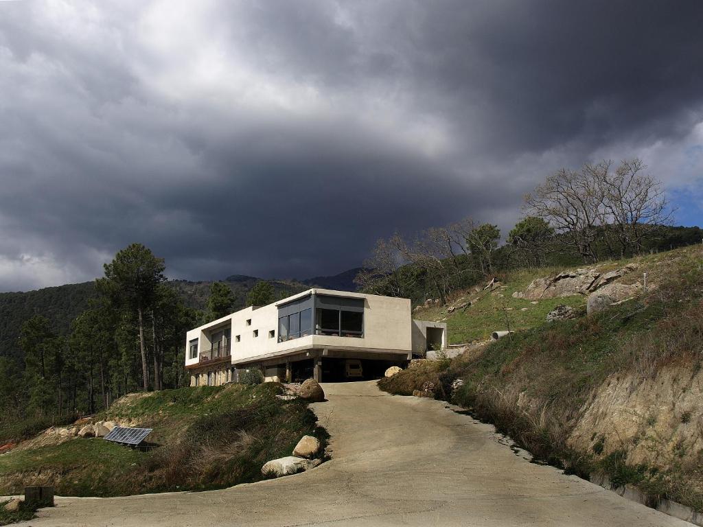 ein Haus auf einem Hügel mit einer unbefestigten Straße in der Unterkunft Hotel La Canela in Piedralaves
