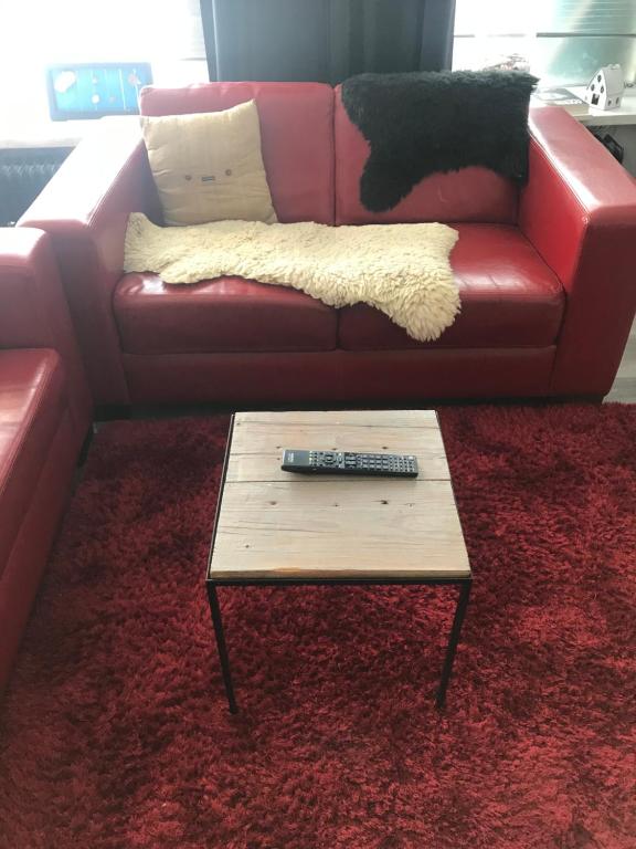 een rode leren bank met afstandsbediening op een salontafel bij Bed & Breakfast Klokgaaf in De Koog