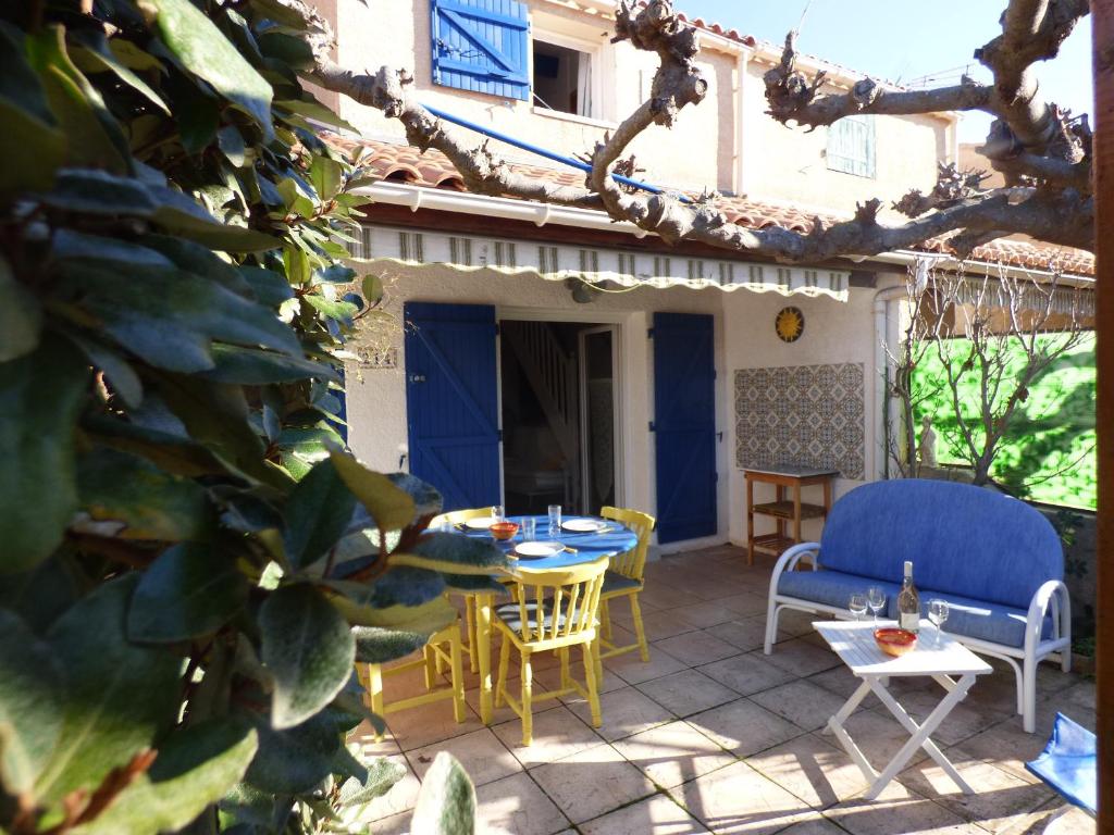 a patio with a table and chairs and a blue door at Joli Pavillon 2** Narbonne Plage in Narbonne-Plage