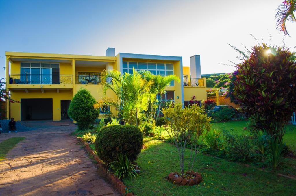 a yellow house with palm trees in front of it at Room in Villa - The elegant Villa Alexandre near Ivato Airport in Antananarivo