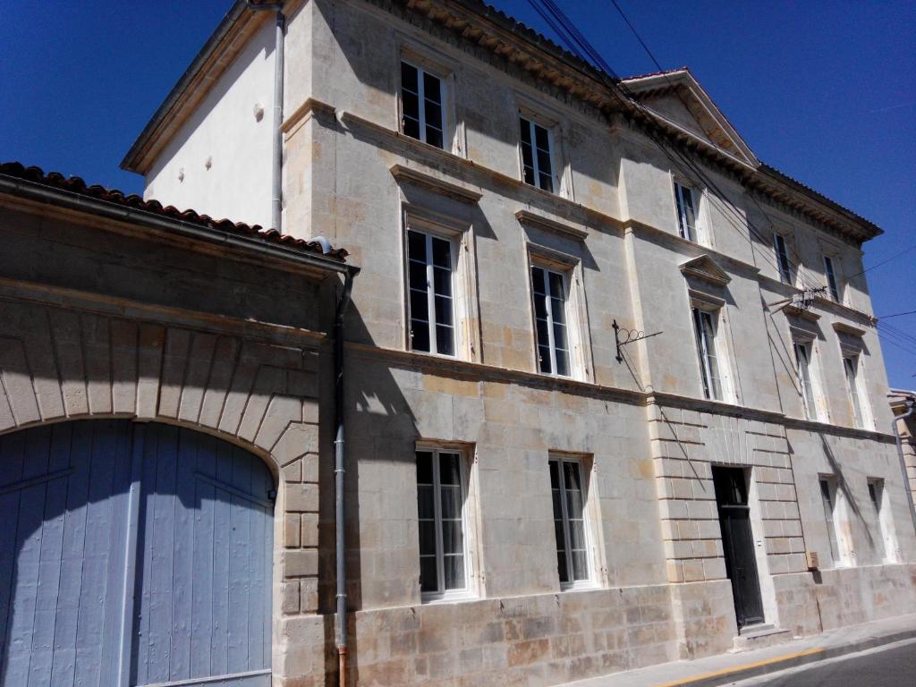 um grande edifício de tijolos com portas e janelas brancas em Chambres d'hôtes -- Le Clos de Gémozac em Gémozac