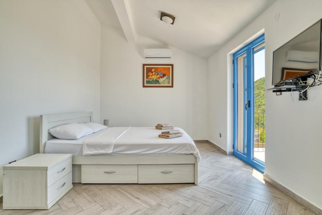 a white bedroom with a bed and a window at Villa Old Olive in Budva
