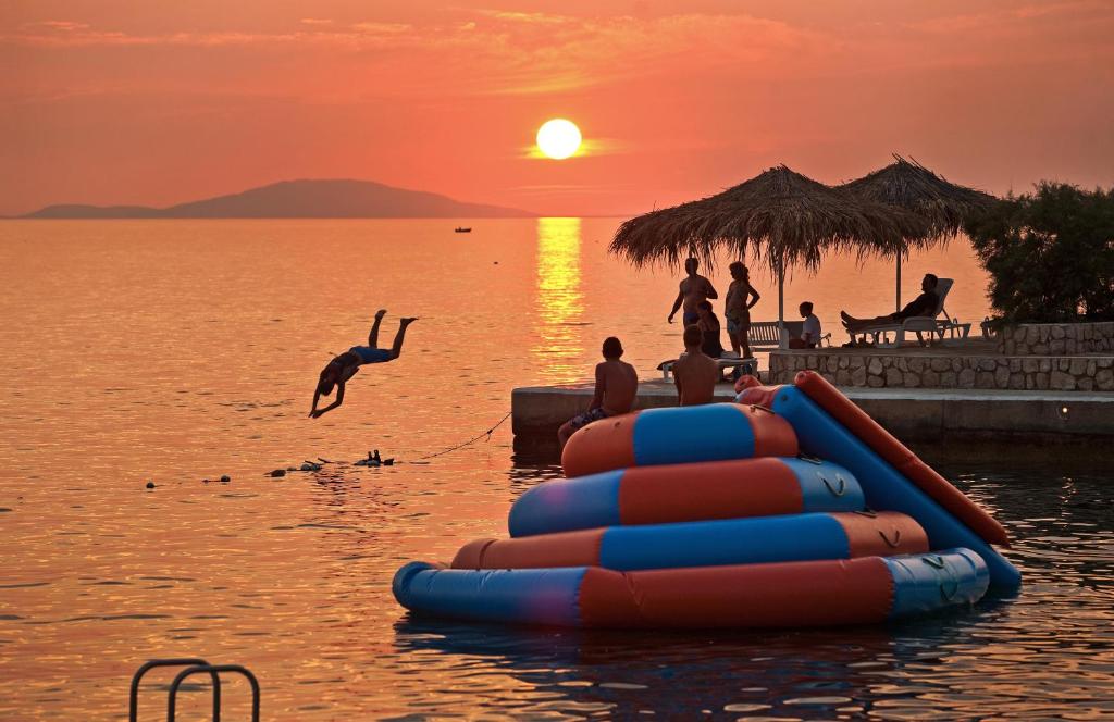 grupa ludzi bawiących się w wodzie o zachodzie słońca w obiekcie Holiday Park Mandrice w mieście Mandre