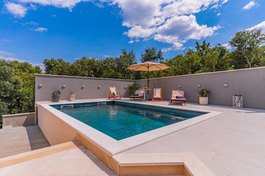 una piscina al aire libre con muebles de exterior y sombrilla en Luxury Nest Maretta & Oliva, en Korčula