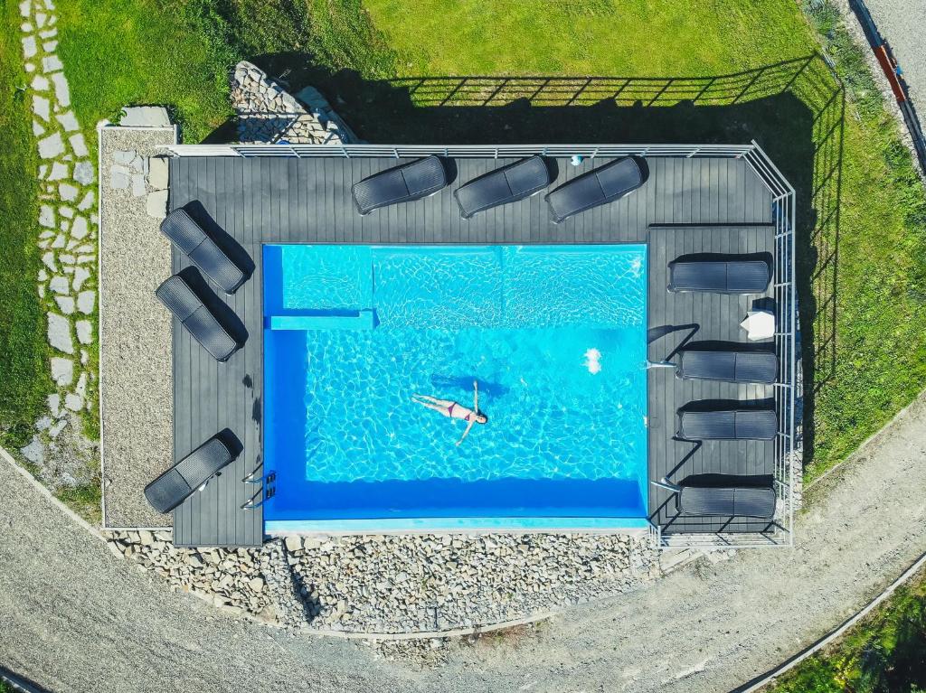 Aerial view of a rectangular outdoor pool with a lone swimmer floating, surrounded by lounge chairs.