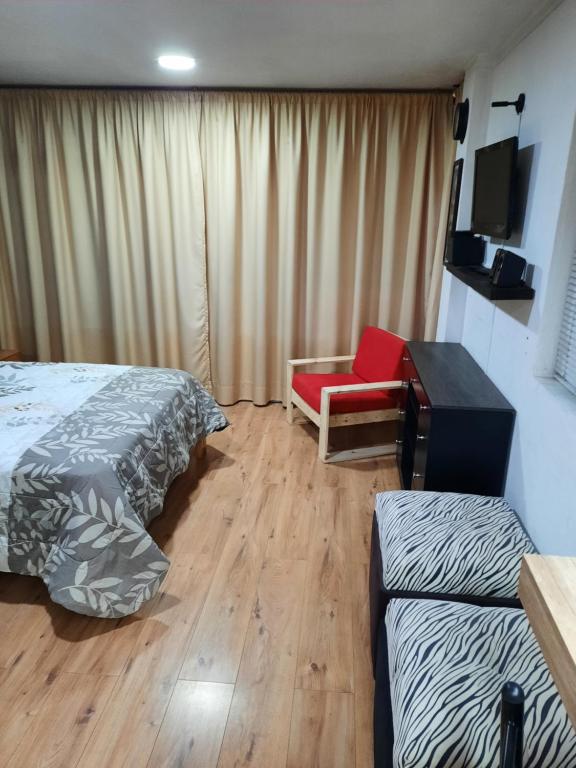 Pokój z 2 łóżkami, krzesłem i biurkiem w obiekcie Hospedaje Aguaclara w mieście Quito
