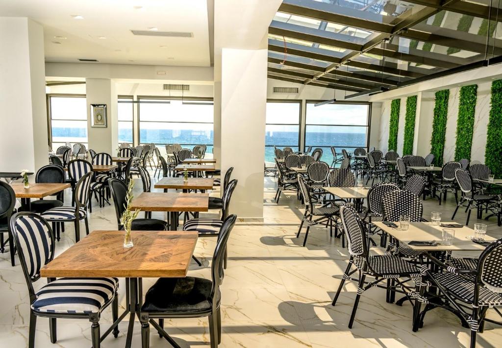 an empty restaurant with tables and chairs and the ocean at Mythical Coast Wellness Retreat in Mytilene