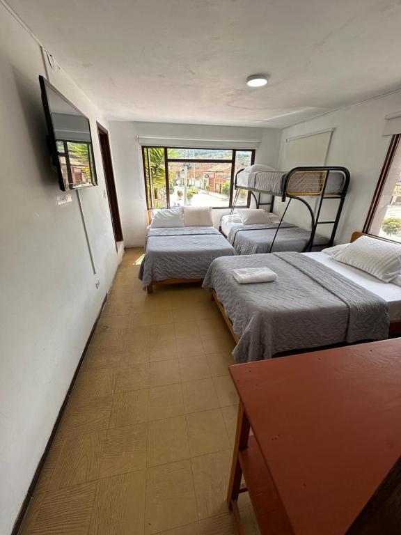 a room with three beds and a window at Hotel Rook INN in Paipa