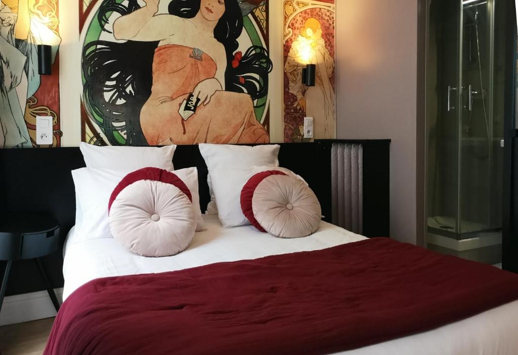a bedroom with a bed with pillows and a painting at Hotel Hippodrome in Paris