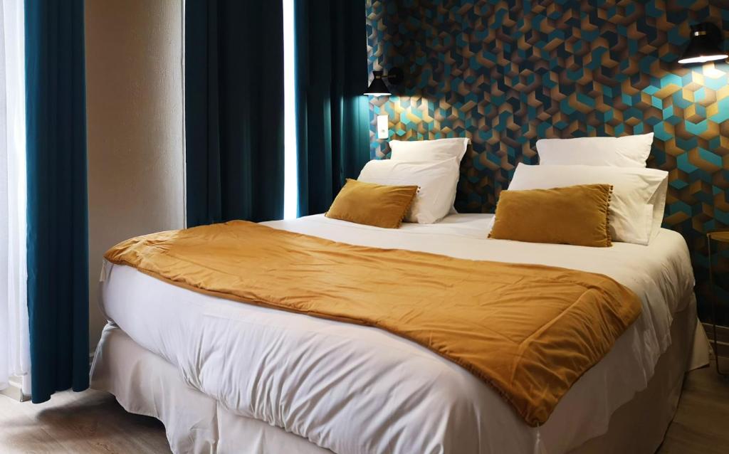 パリにあるホテル ヒッポドロームのベッドルーム1室(白いシーツと黄色い枕の大型ベッド1台付)