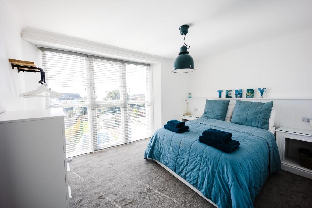 1 dormitorio con cama con sábanas azules y ventana en Flat 3 Flint House Tenby - Luxury couples apartment, en Tenby