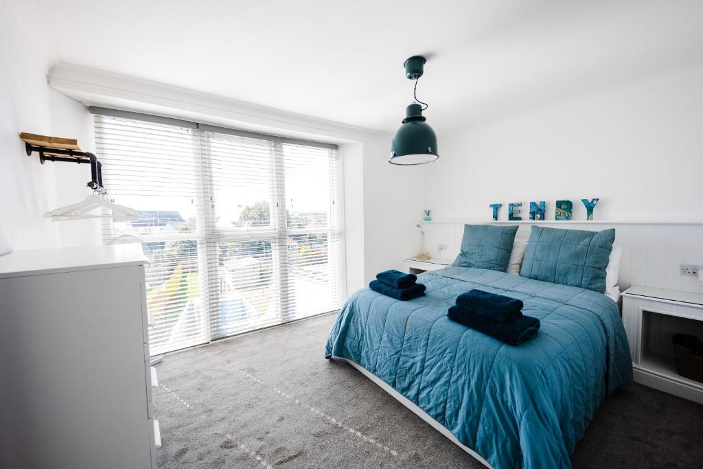 a bedroom with a bed with blue sheets and a window at Flat 3 Flint House Tenby - Luxury couples apartment in Tenby