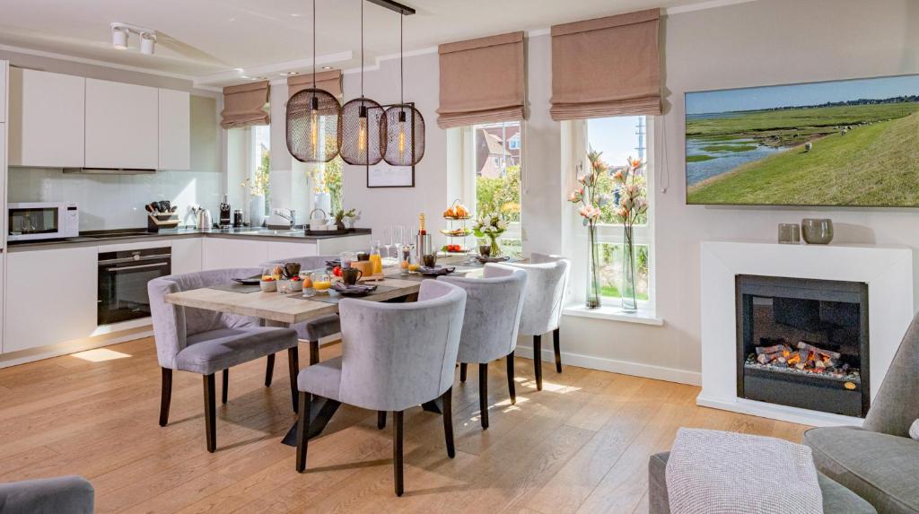 een eetkamer met een tafel en stoelen en een open haard bij Ferienhaus Witthüs - Domizil Silbermöwe - exklusiv, strand- und zentrumsnah in Westerland