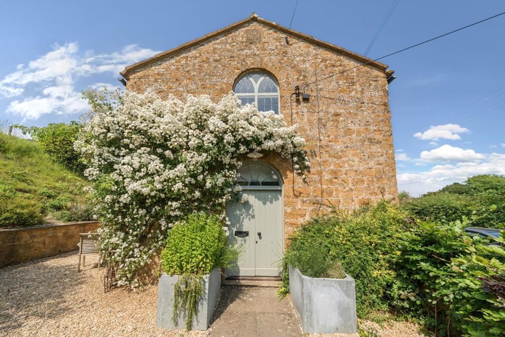 a brick building with a white door and a flowering tree at The Old Chapel in Beaminster