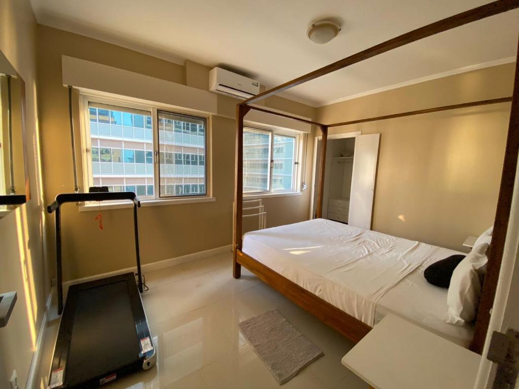 um quarto com uma cama e duas janelas em The Queen em Luanda