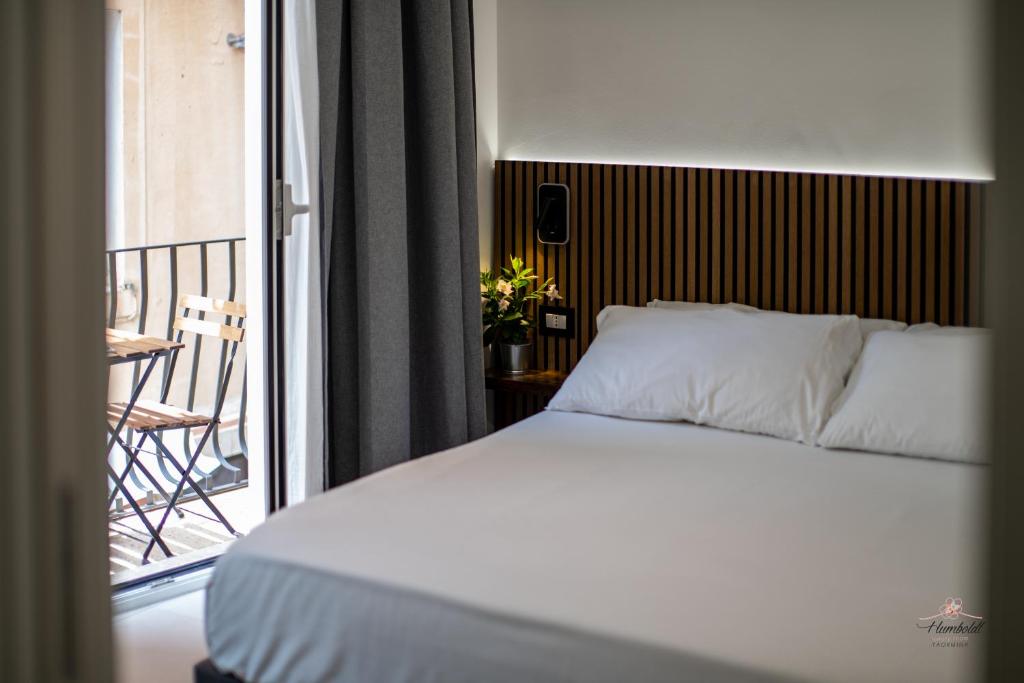 a bedroom with a bed and a balcony with a chair at Humboldt Luxury Room Taormina in Taormina