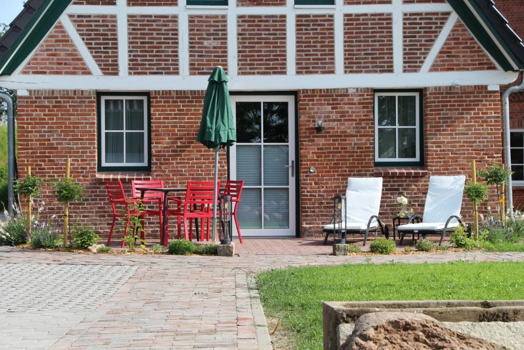 Una casa de ladrillo con una mesa y sillas y una sombrilla. en Ferienhaus Alwine, en Jork