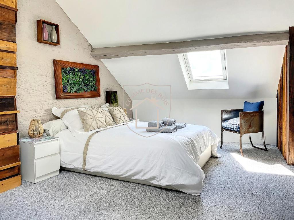 een slaapkamer met een groot wit bed en een stoel bij Le Donjon des Rois in Dourdan
