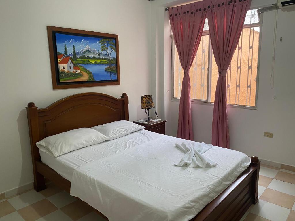 Schlafzimmer mit einem Bett mit weißer Bettwäsche und einem Fenster in der Unterkunft Hotel Los Corales Tulua in Tuluá