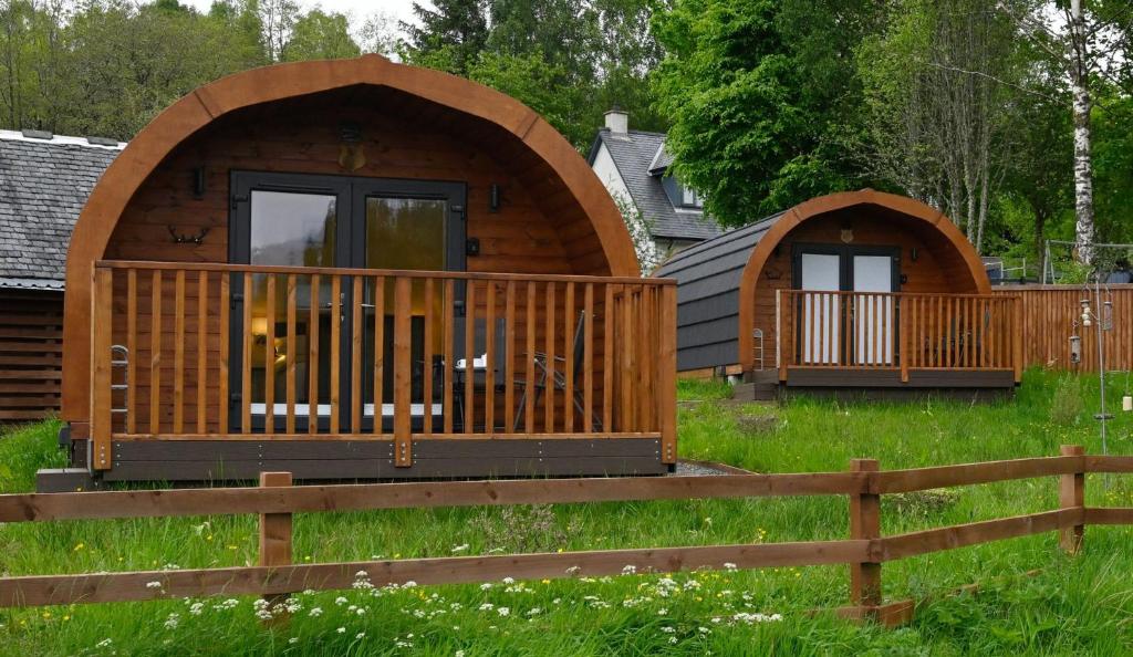 a log cabin with a deck and a fence at Squirrel Lodge in Roybridge