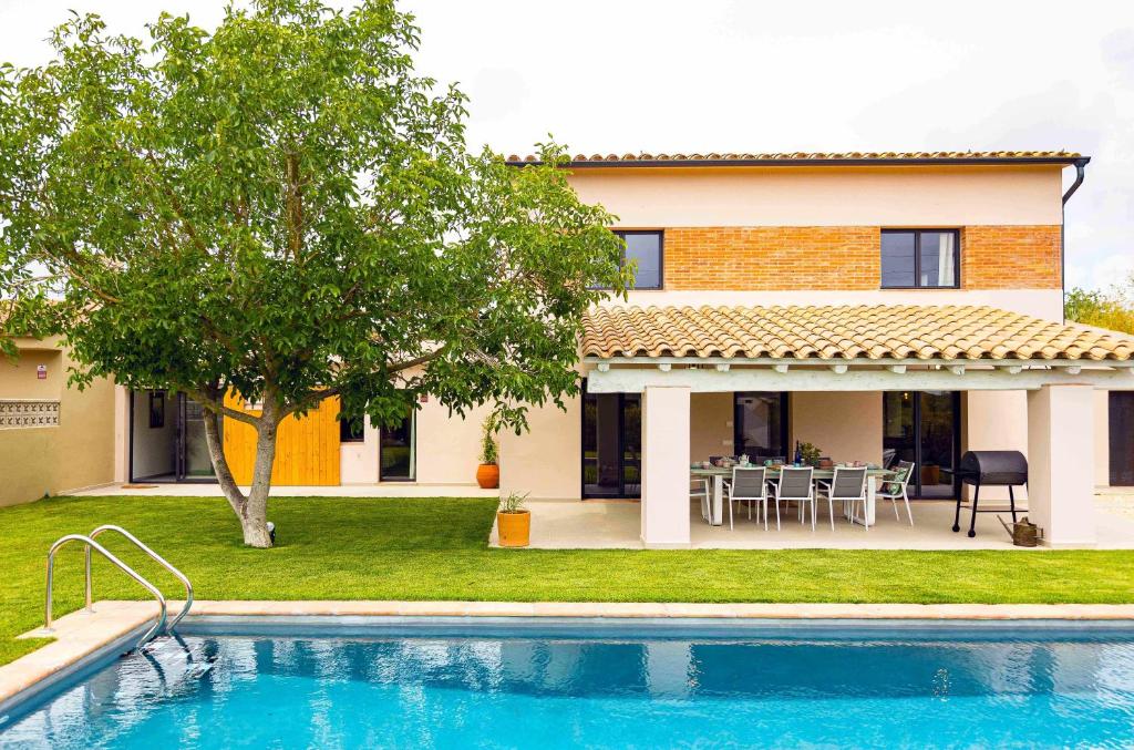 eine Villa mit einem Pool vor einem Haus in der Unterkunft Can Candiu Establecimiento de 2 casas enteras in Vall-llobrega