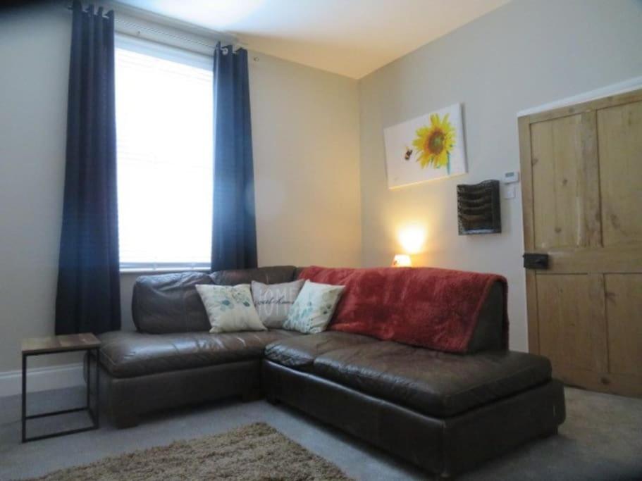 uma sala de estar com um sofá de couro e uma janela em 2 Railway Terrace 