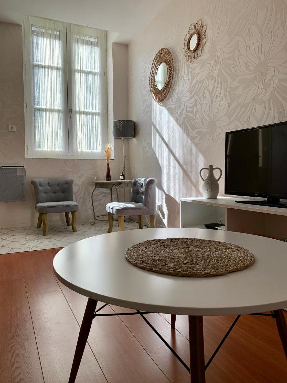 un salon avec une table et une télévision dans l'établissement Chouette Appartement Dijon Centre, à Dijon