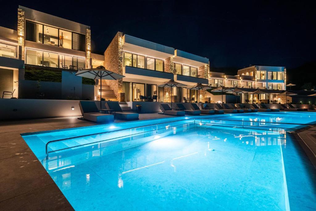 a swimming pool in front of a building at night at The View Hotel Sofas Coastal Retreat in Perdika