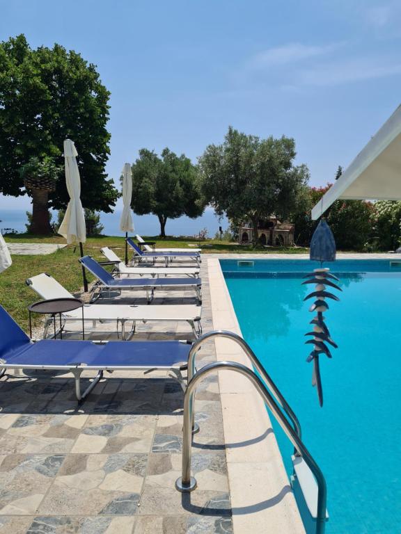 a row of lounge chairs next to a swimming pool at Greco Paradise Suites - ADULT ONLY in Nea Skioni