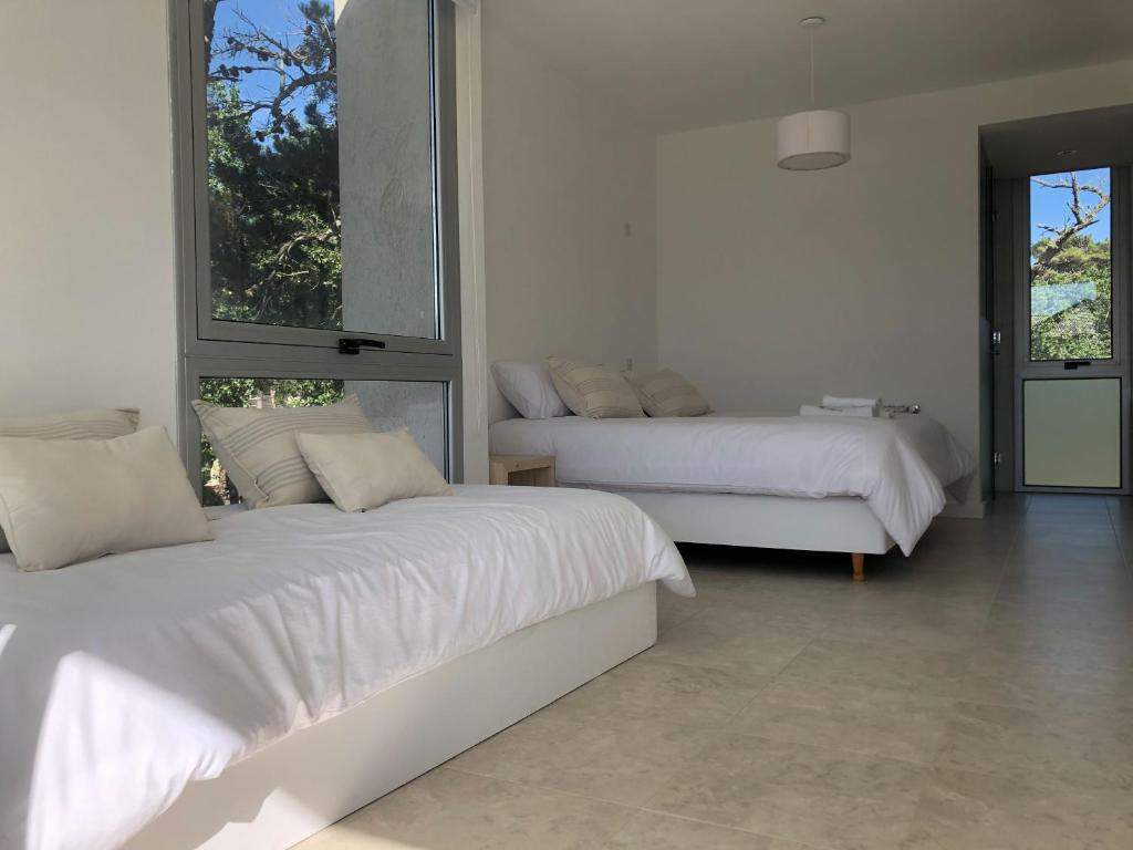 biała sypialnia z 2 łóżkami i oknem w obiekcie Carilo Vista w mieście Carilo