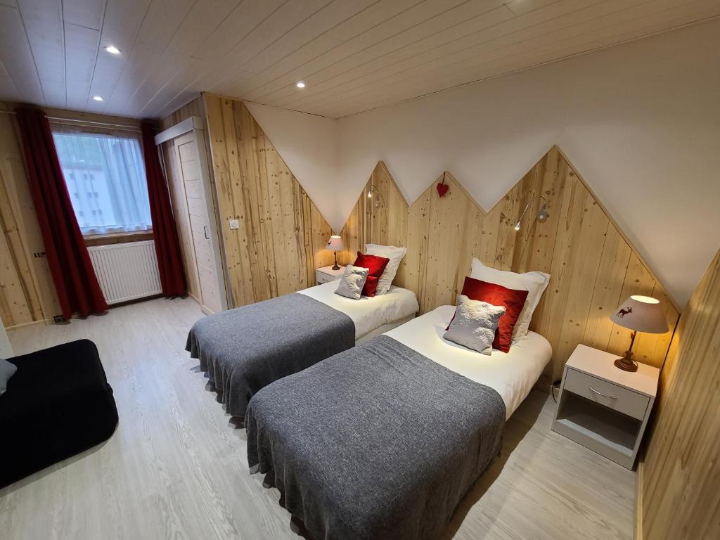 two beds in a room with wooden walls at Hôtel du Centre in Valloire