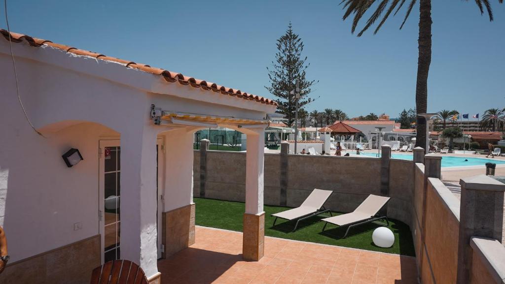 a patio with two lounge chairs and a swimming pool at BUNGALOW LOS ARCOS in Maspalomas