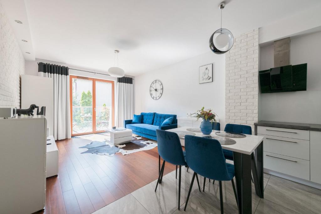 a kitchen and living room with a table and blue chairs at Dom & House - Apartments Sopot Kamienny Potok in Sopot