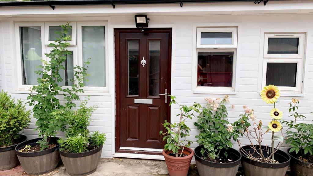 a front door of a house with potted plants at Mon Repos Heathrow - Hatton Cross Station 2 Stops from Heathrow Underground Free WiFi Free Parking Free Refreshments in New Bedfont