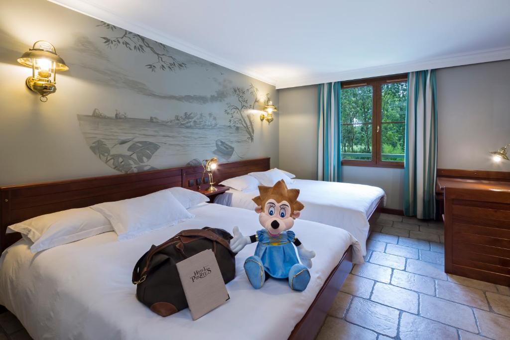 een hotelkamer met twee bedden en een knuffeldier erop bij Hôtel Des Pirates in Dolancourt