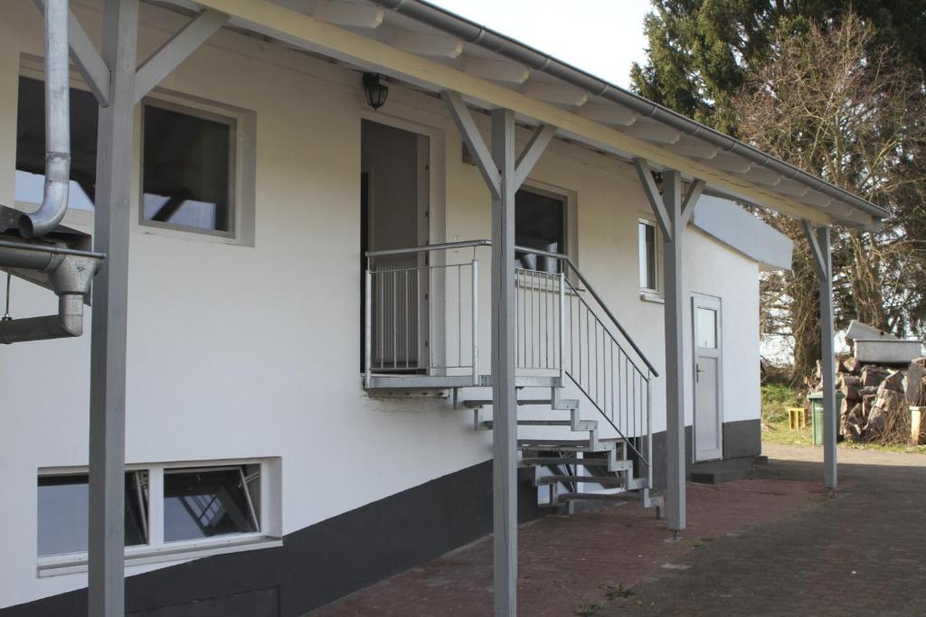 a white building with a staircase on the side of it at Ruhige Ferienwohnungen mit Teichblick in Wetterfeld