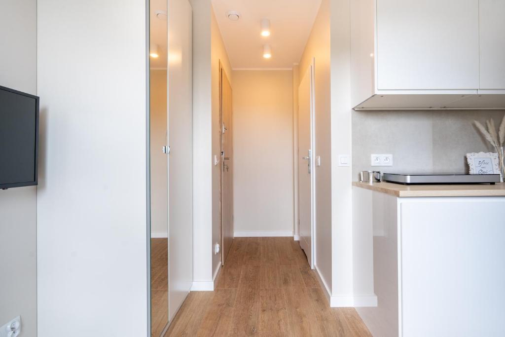 a kitchen with white cabinets and a wooden floor at Brzeźno Studio Deluxe in Gdańsk