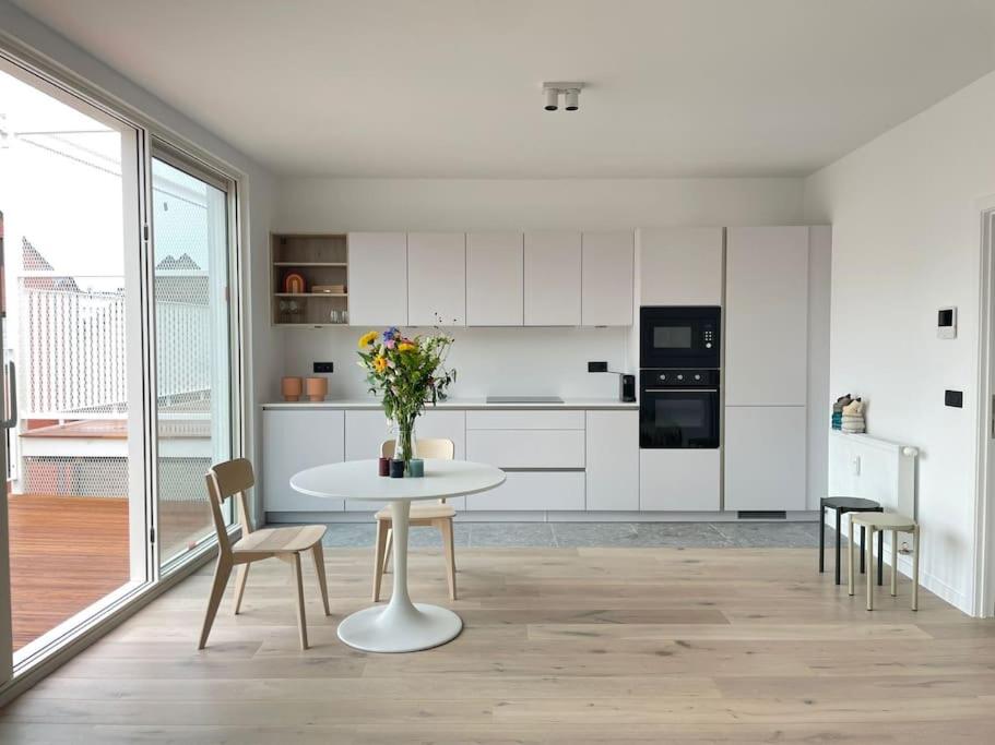 een witte keuken met een witte tafel en stoelen bij #2800ourhome 301 in Mechelen