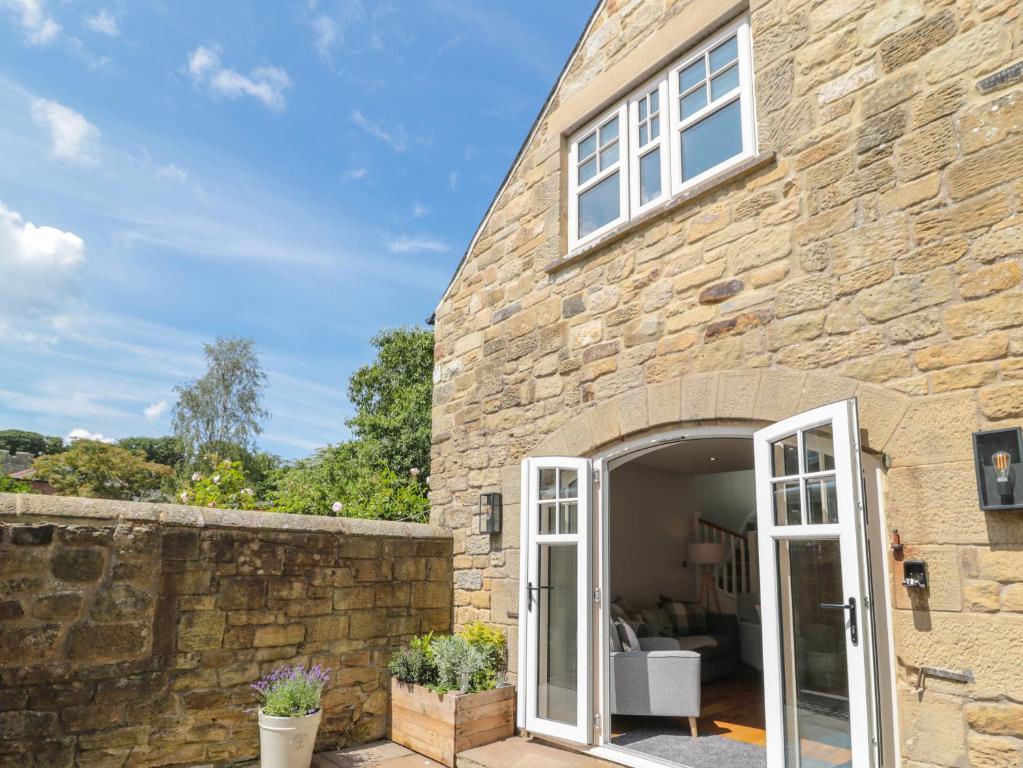 a stone house with an open door at Willow Cottage in Morpeth