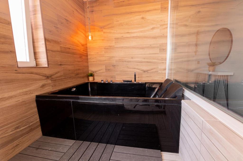 baño con bañera negra y paredes de madera en Torre 2 planta 11, en Fuengirola