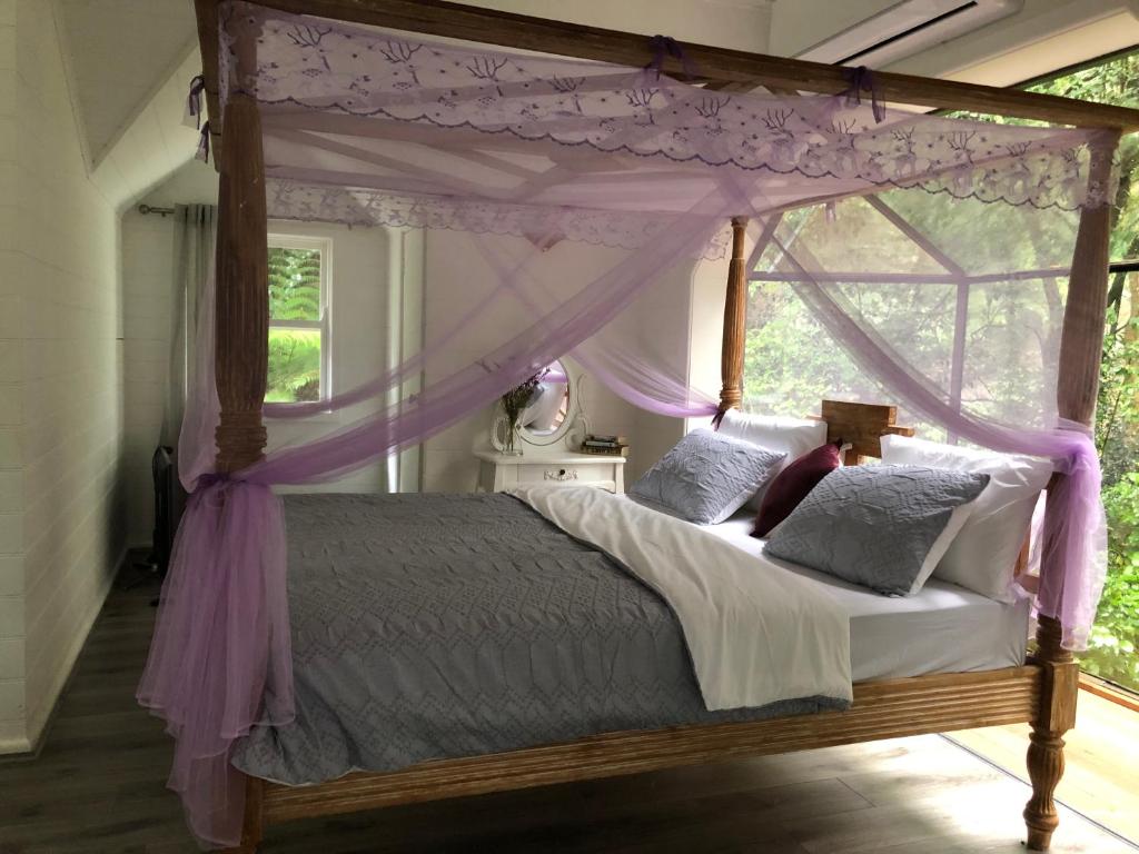a bedroom with a canopy bed with a window at The Whitehouse in Sassafras