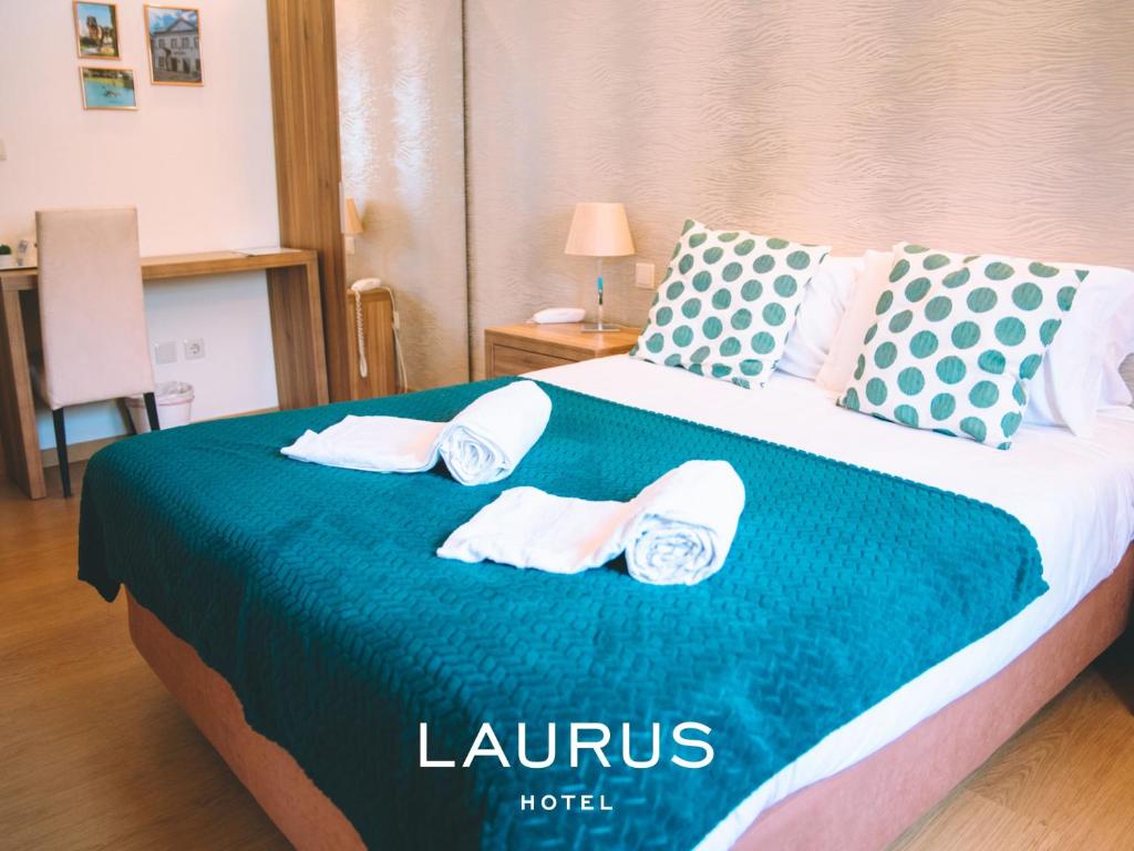 a hotel room with a large bed with towels on it at Laurus Hotel in Lourinhã