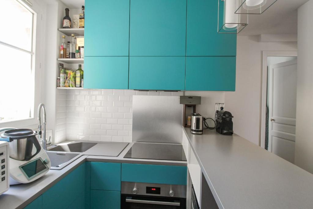 a kitchen with blue cabinets and a sink at Charming and luminous 2br with balcony - Boulogne-Billancourt - Welkeys in Boulogne-Billancourt