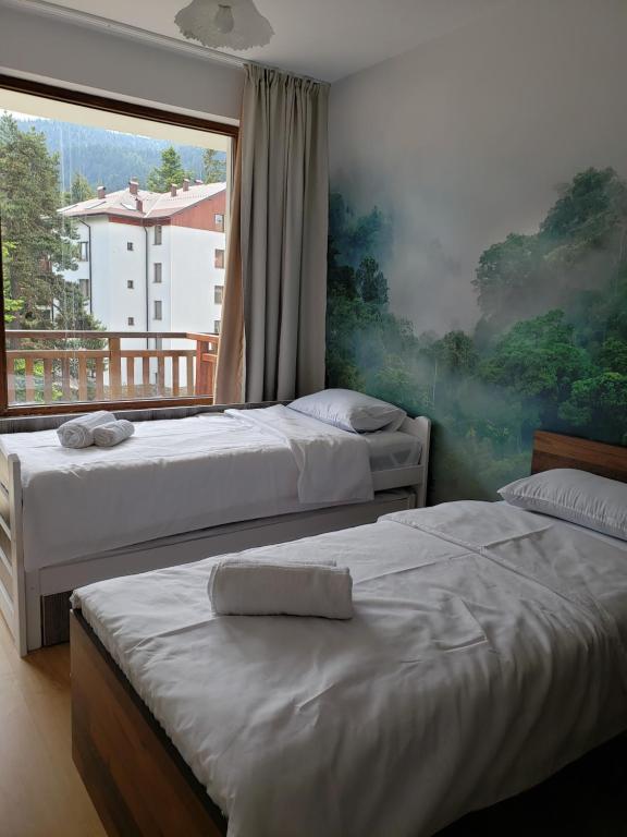 a bedroom with two beds and a large window at 2 bedroom "Pine Hug" apartment in Borovets