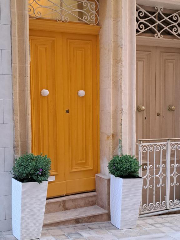 żółte drzwi z dwoma doniczkami przed nimi w obiekcie Ta' Wenzu w mieście Birgu