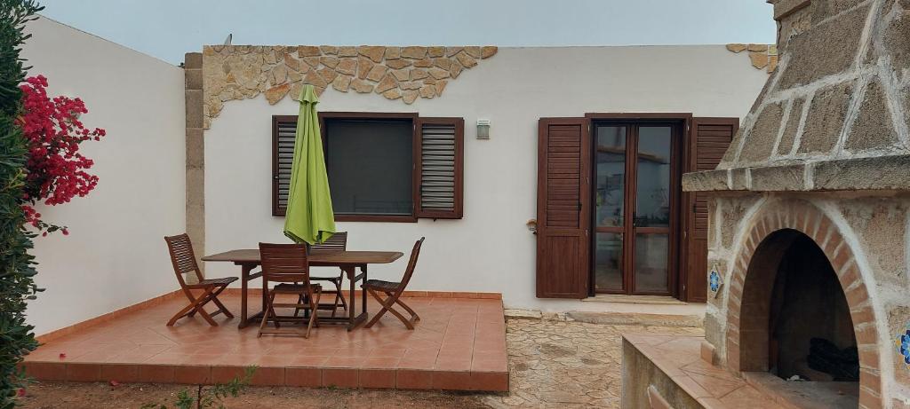 eine Terrasse mit einem Tisch, Stühlen und einem Sonnenschirm in der Unterkunft Casa Sirio in Favignana