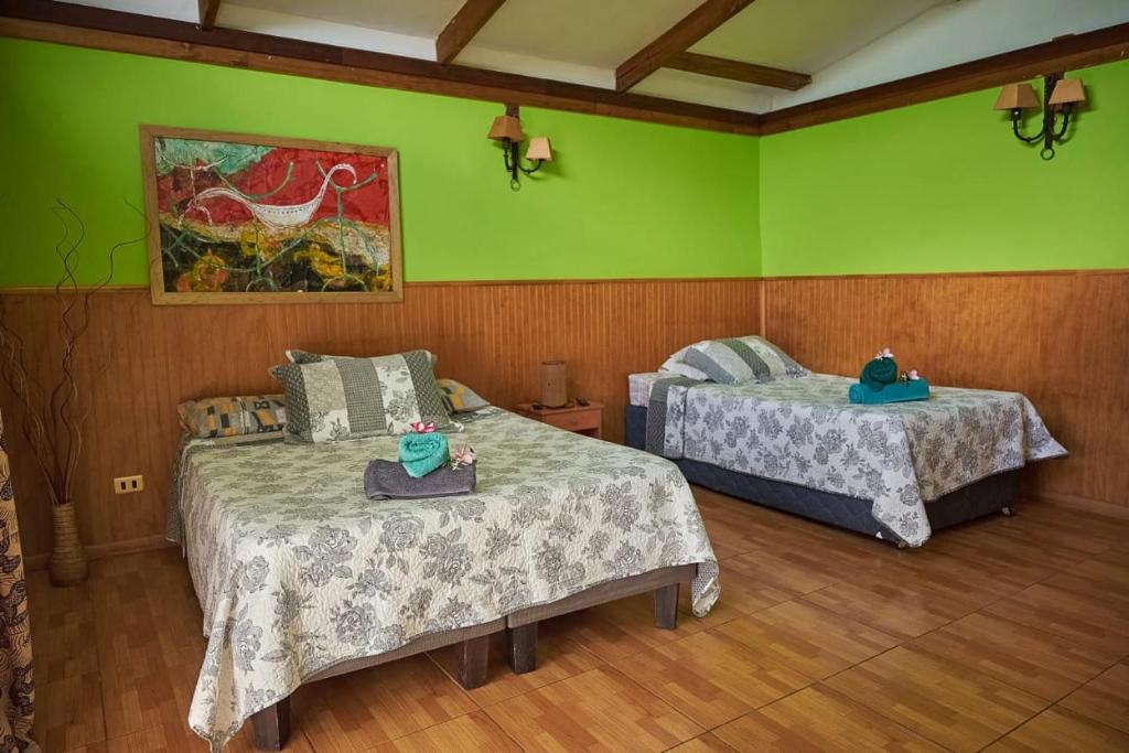 two beds in a room with green walls at Cabañas Maria Hau in Hanga Roa