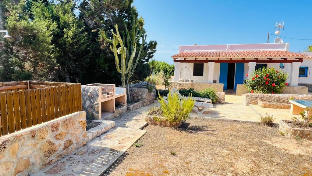 a backyard with a stone wall and a house at Casa Vicent Campanitx Es Pujols in Es Pujols